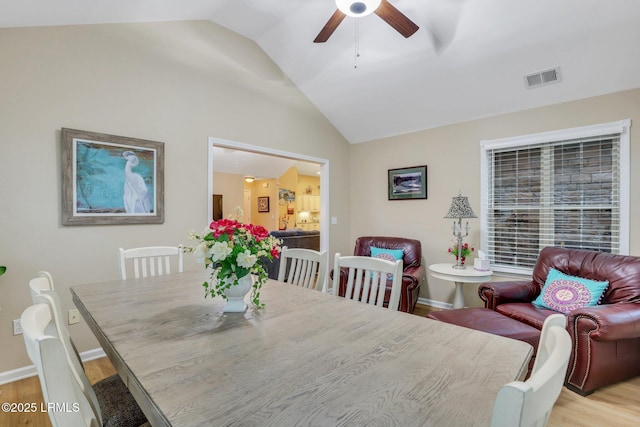 dining space with ceiling fan, lofted ceiling, and light hardwood / wood-style flooring