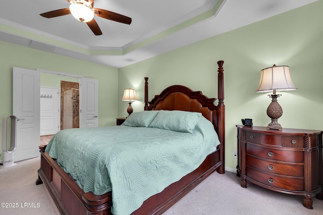 carpeted bedroom with ornamental molding, a tray ceiling, and a ceiling fan