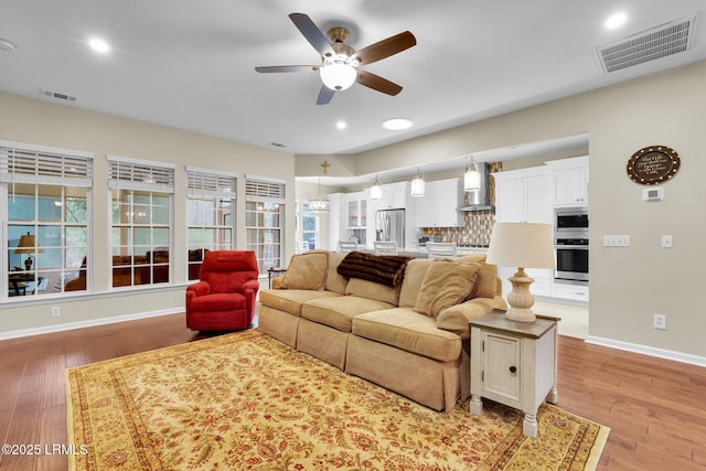 living room featuring baseboards, visible vents, and light wood-style floors