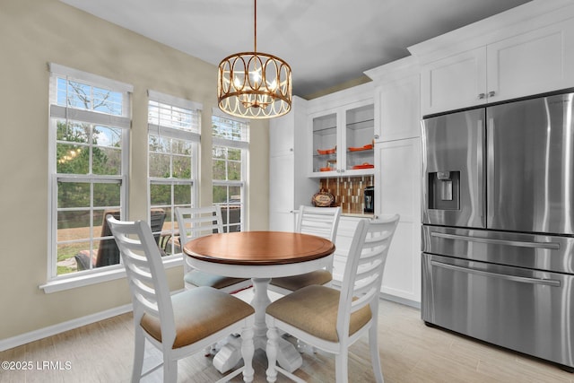 dining room featuring light wood finished floors, baseboards, and a chandelier