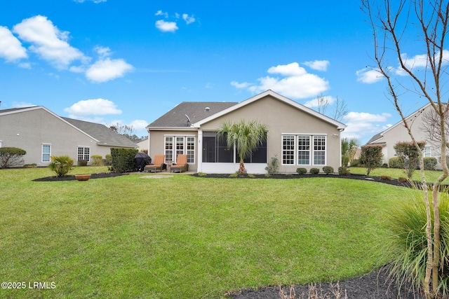 rear view of property with a yard, a sunroom, and stucco siding