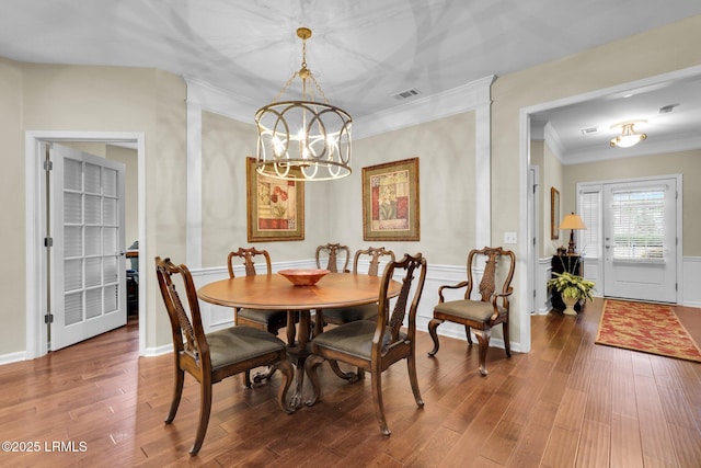 dining space with a chandelier, ornamental molding, wood finished floors, and visible vents