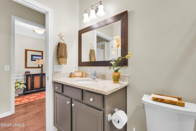 bathroom with baseboards, vanity, toilet, and wood finished floors