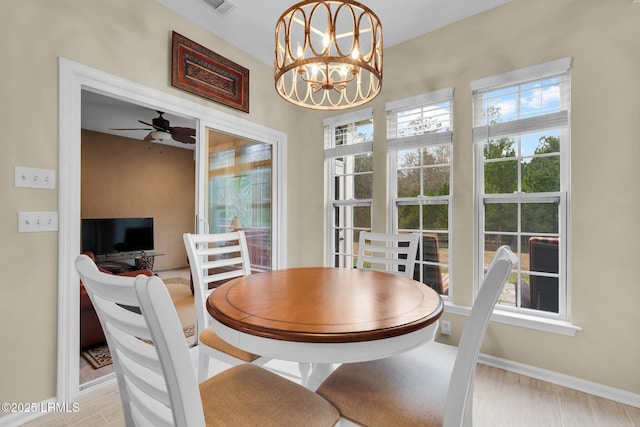 dining area with ceiling fan with notable chandelier, baseboards, and wood finished floors