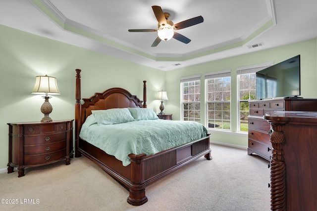 carpeted bedroom featuring baseboards, a tray ceiling, visible vents, and crown molding