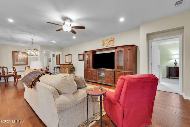 living area featuring ceiling fan with notable chandelier, hardwood / wood-style floors, visible vents, and recessed lighting