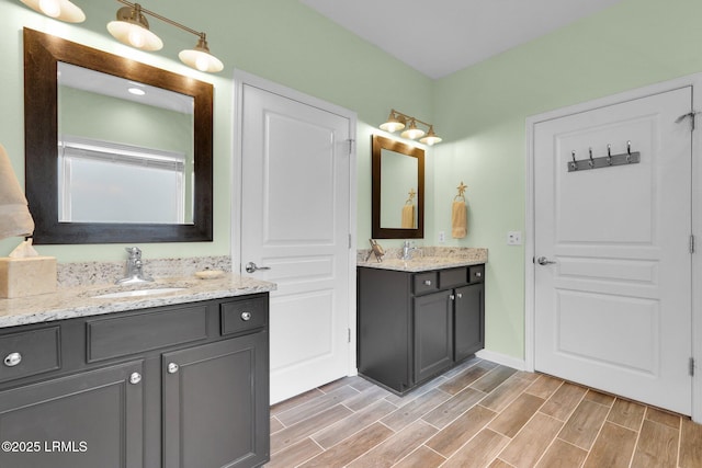 full bath featuring two vanities, a sink, and wood finish floors