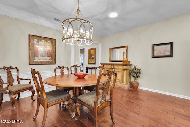 dining area featuring hardwood / wood-style flooring, baseboards, visible vents, and a chandelier