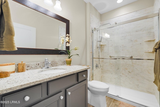 bathroom featuring a stall shower, vanity, toilet, and wood finished floors