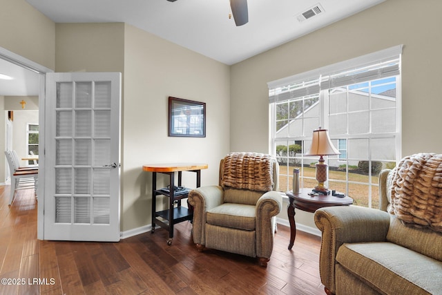 living area with visible vents, ceiling fan, baseboards, and hardwood / wood-style flooring