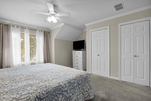 carpeted bedroom with ornamental molding, two closets, and ceiling fan