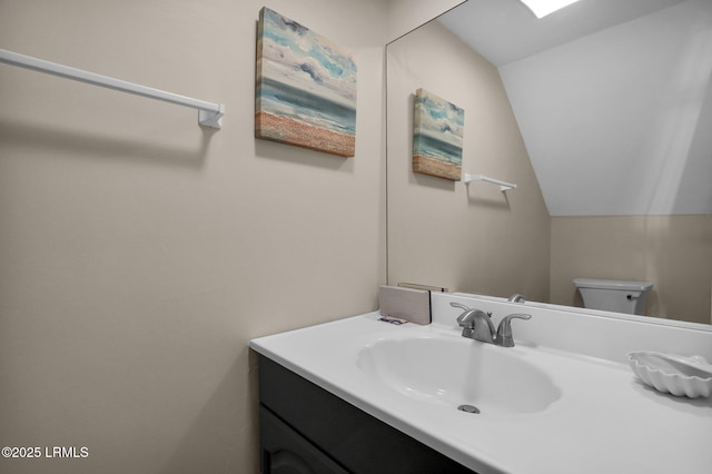 bathroom featuring lofted ceiling, vanity, and toilet