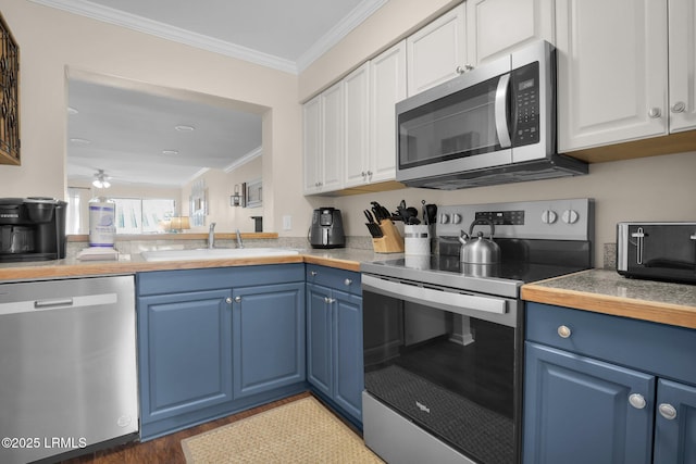 kitchen featuring sink, white cabinetry, stainless steel appliances, ornamental molding, and blue cabinets