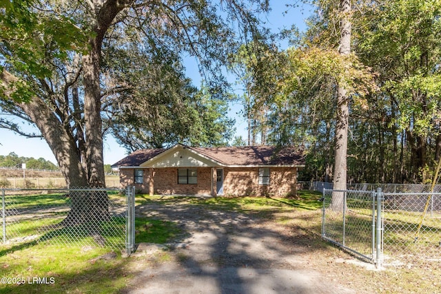 ranch-style house featuring brick siding, a front lawn, fence, and a gate