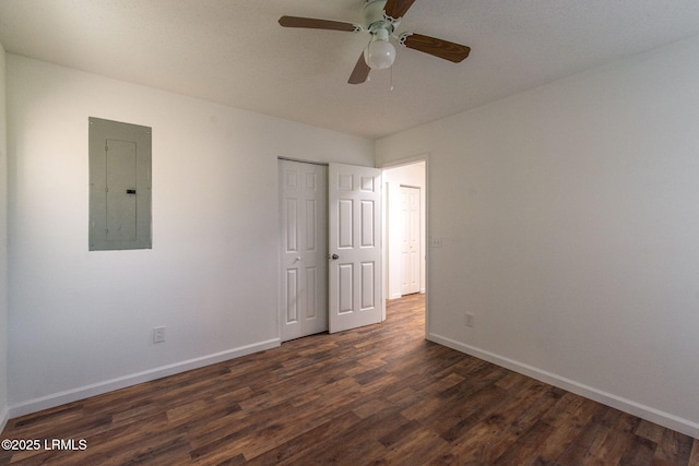 unfurnished bedroom with dark wood-style floors, a closet, a ceiling fan, electric panel, and baseboards