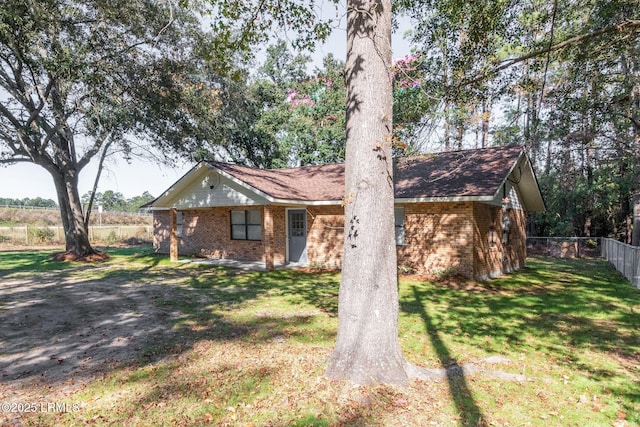 single story home featuring brick siding, fence, and a front lawn