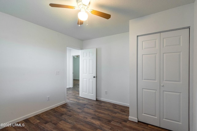 unfurnished bedroom featuring dark wood-style floors, a closet, baseboards, and a ceiling fan