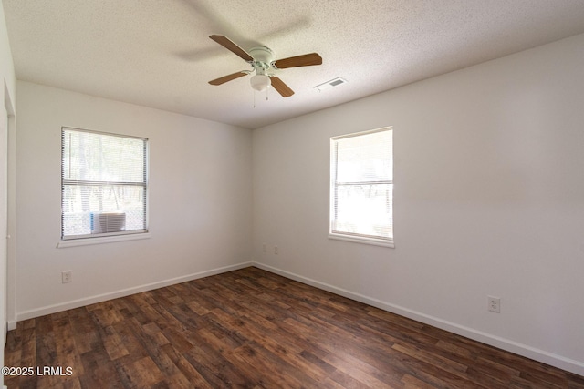 spare room featuring dark wood-style floors, visible vents, a ceiling fan, a textured ceiling, and baseboards