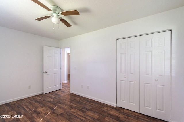 unfurnished bedroom featuring dark wood-type flooring, a closet, and baseboards