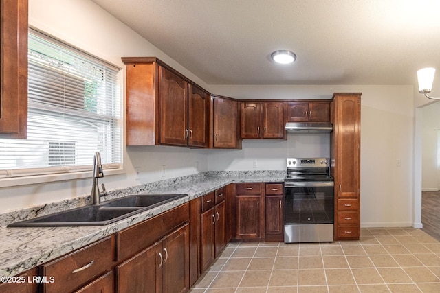 kitchen with light stone counters, light tile patterned floors, a sink, stainless steel range with electric stovetop, and under cabinet range hood