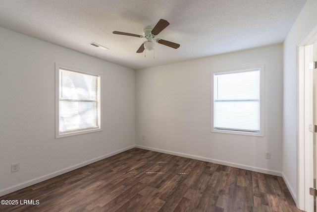 unfurnished room with dark wood-type flooring, a wealth of natural light, visible vents, and a textured ceiling