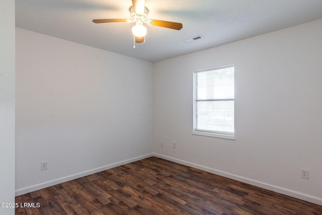 unfurnished room featuring a ceiling fan, visible vents, baseboards, and dark wood-type flooring