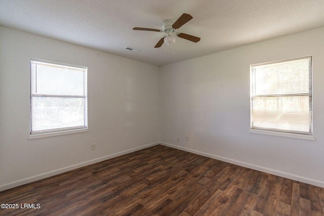 spare room featuring dark wood-style floors, visible vents, and a healthy amount of sunlight