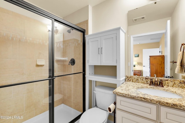 bathroom with vanity, a shower with shower door, and toilet