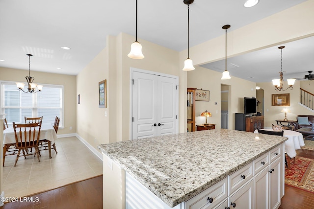 kitchen with an inviting chandelier, light stone counters, decorative light fixtures, and white cabinets