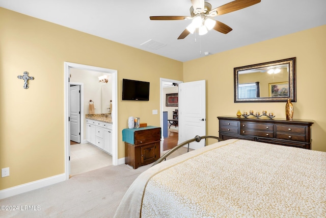 bedroom with light carpet, connected bathroom, and ceiling fan