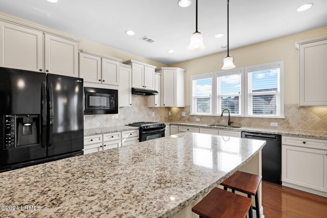 kitchen featuring pendant lighting, sink, backsplash, and black appliances