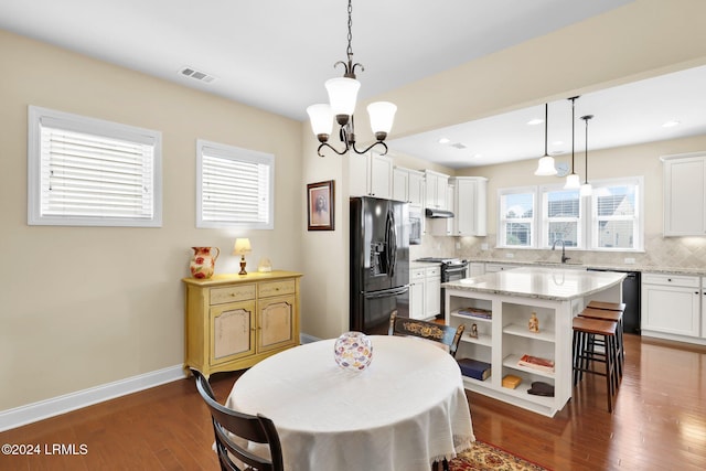 dining room featuring dark wood-type flooring, sink, and an inviting chandelier