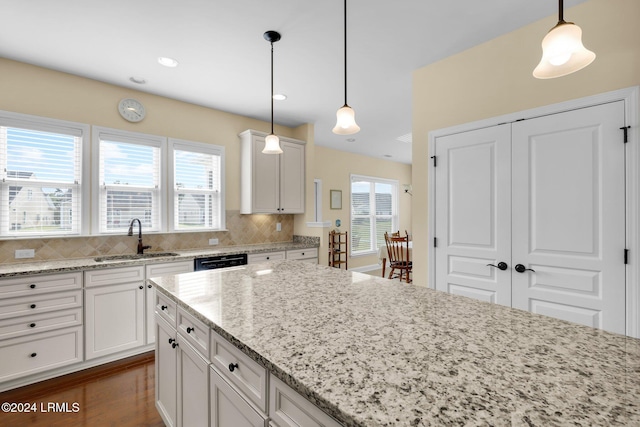 kitchen featuring pendant lighting, light stone countertops, sink, and decorative backsplash