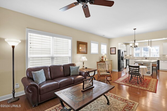 living room featuring ceiling fan with notable chandelier, sink, and light hardwood / wood-style floors