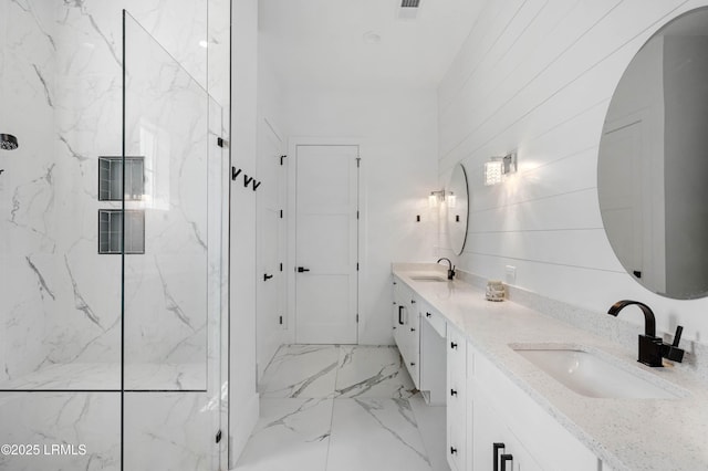 bathroom featuring a marble finish shower, marble finish floor, a sink, and double vanity