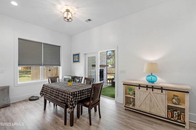 dining area featuring an inviting chandelier, a fireplace, visible vents, baseboards, and wood finished floors