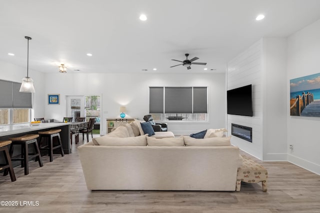 living area with a large fireplace, recessed lighting, and a ceiling fan