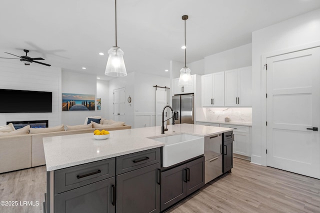 kitchen featuring light wood-style flooring, a sink, appliances with stainless steel finishes, open floor plan, and a ceiling fan