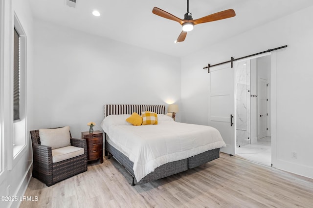 bedroom featuring a barn door, ensuite bathroom, baseboards, light wood-type flooring, and recessed lighting
