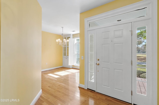 entrance foyer with light wood finished floors, baseboards, and a notable chandelier