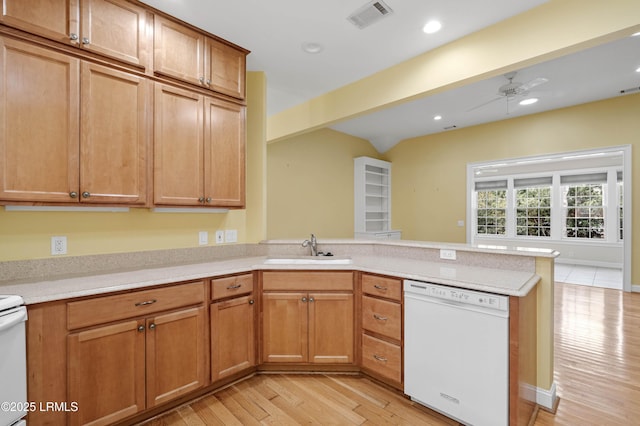 kitchen featuring a sink, dishwasher, light wood-style flooring, a peninsula, and visible vents