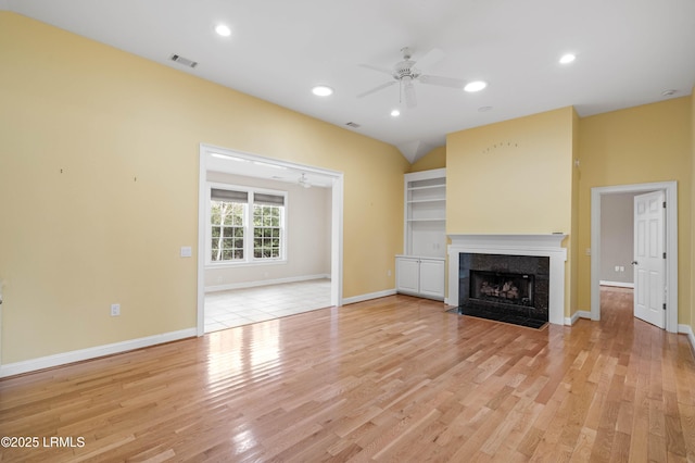 unfurnished living room with recessed lighting, a ceiling fan, light wood-type flooring, baseboards, and a tiled fireplace