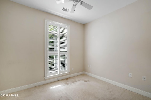 carpeted empty room featuring visible vents, a ceiling fan, and baseboards