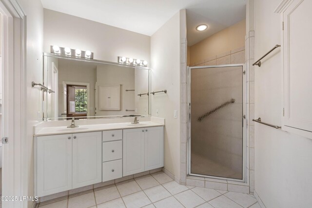 full bathroom featuring tile patterned floors, a sink, a shower stall, and double vanity