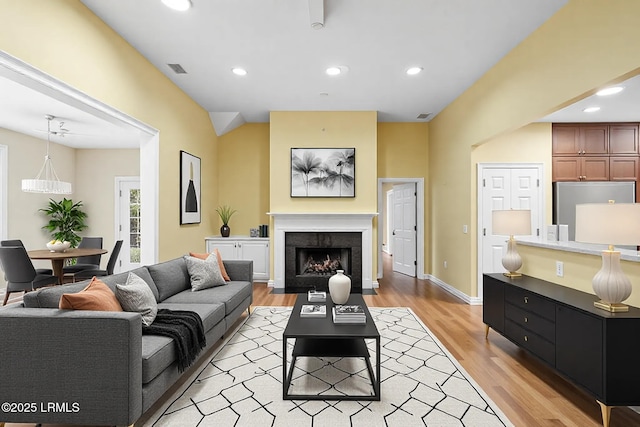 living room with a fireplace with flush hearth, recessed lighting, and light wood-type flooring