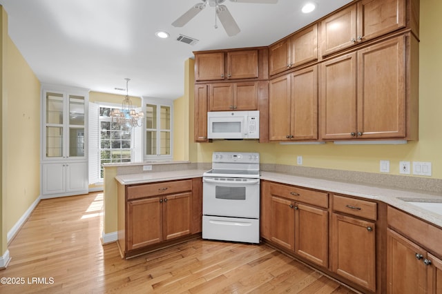 kitchen featuring brown cabinets, white appliances, light wood-style flooring, a peninsula, and visible vents