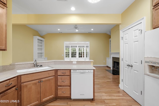 kitchen with a fireplace with flush hearth, a sink, white appliances, a peninsula, and ceiling fan