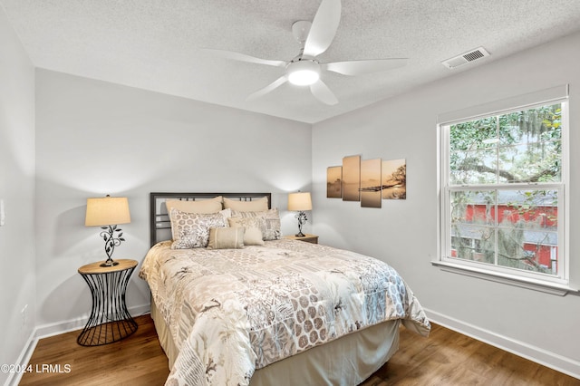 bedroom with hardwood / wood-style floors, a textured ceiling, and ceiling fan