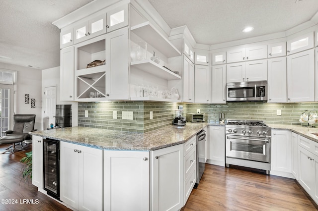 kitchen with appliances with stainless steel finishes, wine cooler, white cabinets, and light stone counters