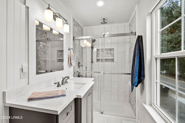 bathroom with vanity, an enclosed shower, and a textured ceiling